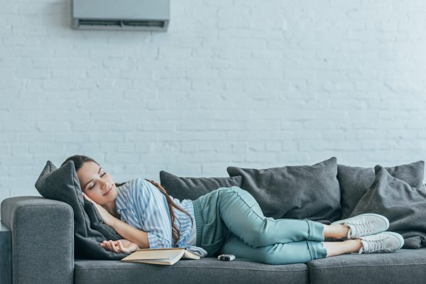 woman sleeping on sofa with book and air conditioner on wall in bartow, fl
