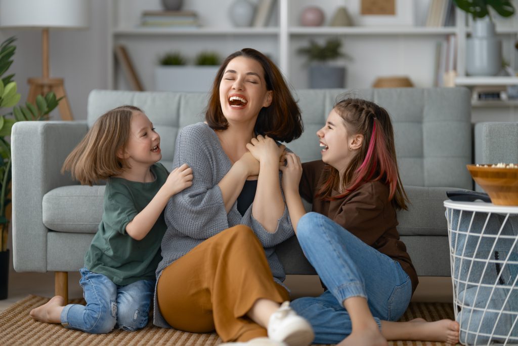 Happy day! Mom and her daughters children girls are playing, smiling and hugging. Family holiday and togetherness.